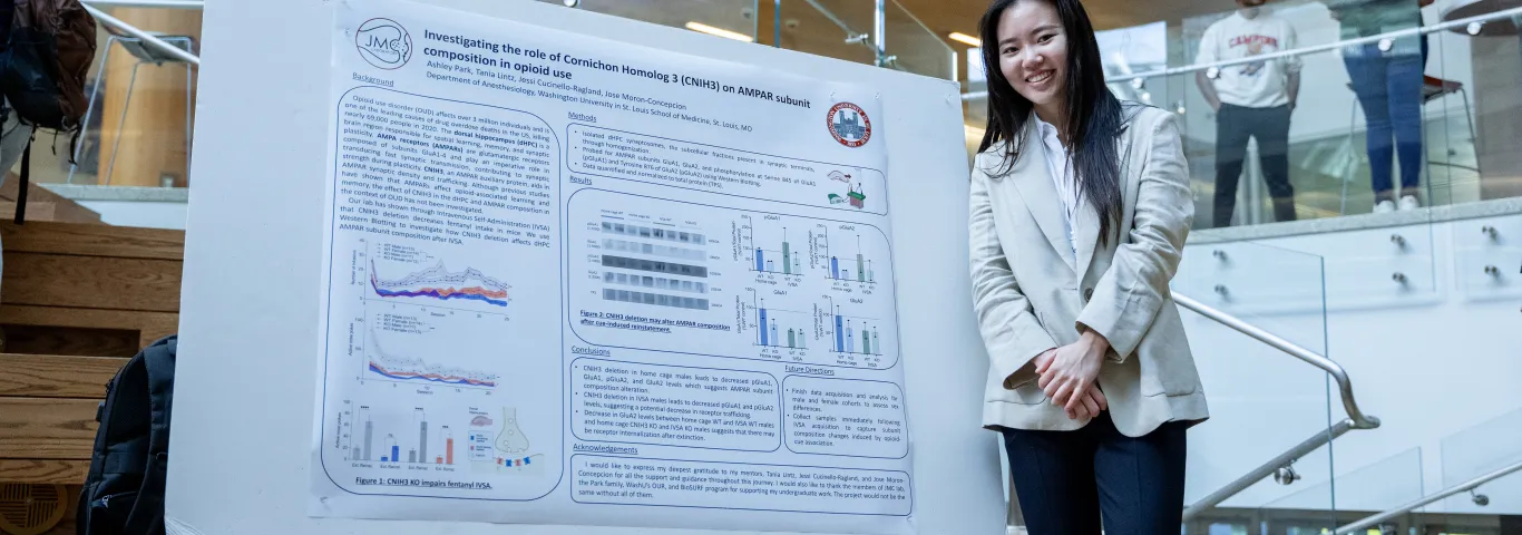 Young woman standing and smiling next to undergraduate research poster